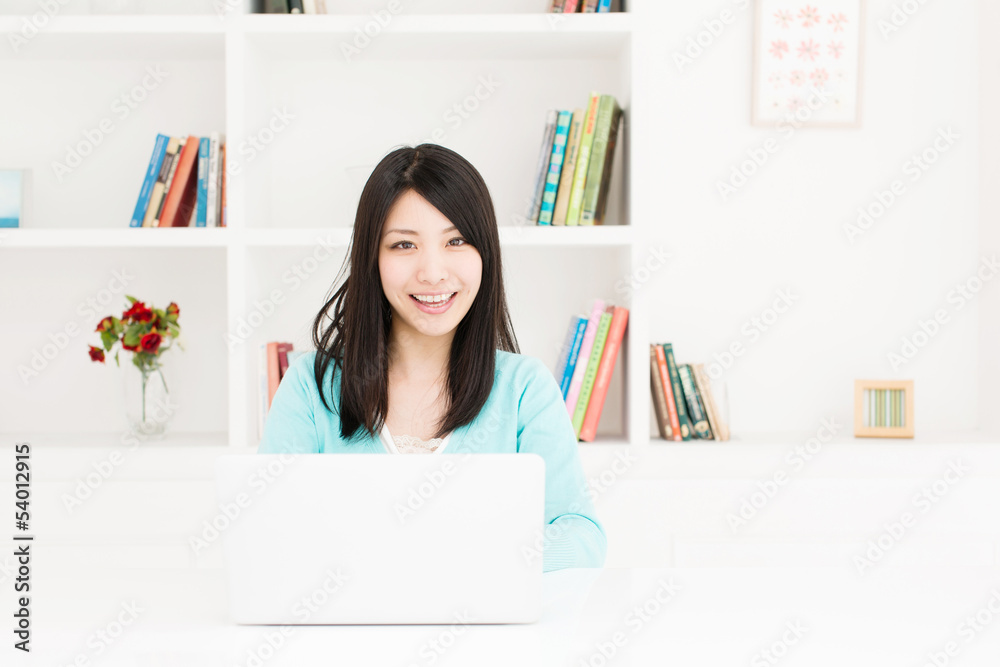 漂亮的亚洲女人在房间里用笔记本电脑