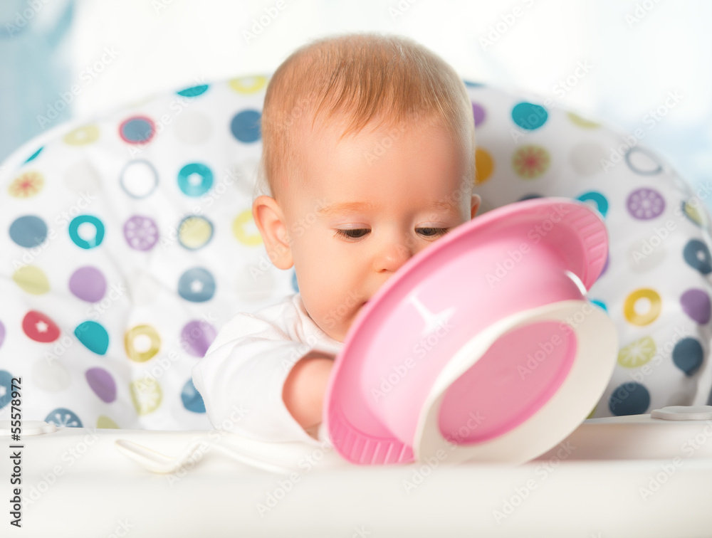 有趣的婴儿正在吃粉红色的盘子