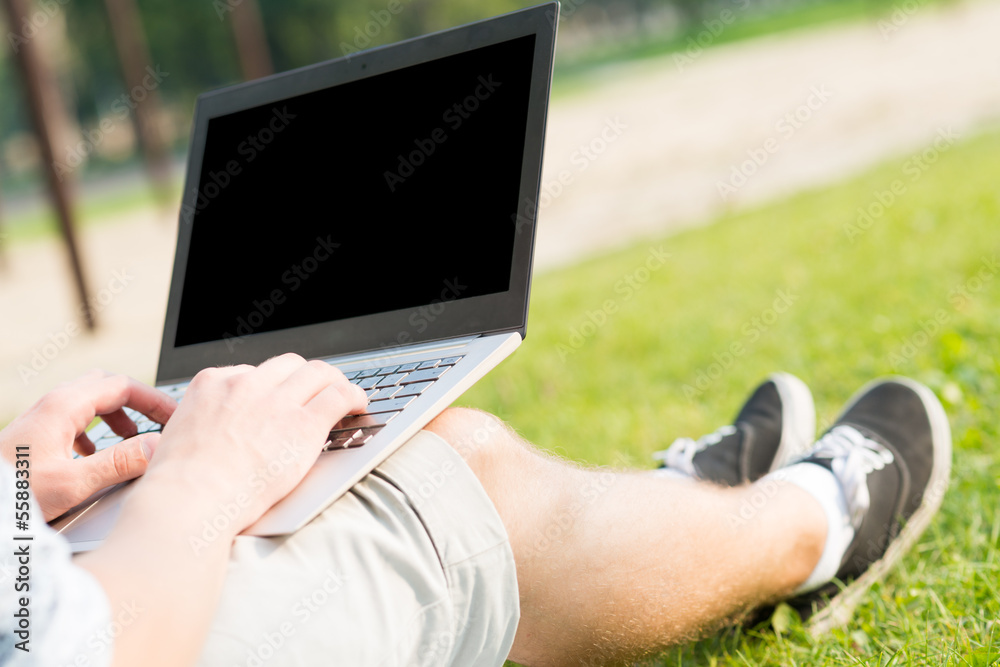 带着笔记本电脑在公园工作的年轻人