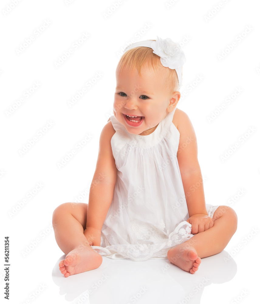 穿着白色连衣裙的快乐小女婴在白色衣服上独自大笑