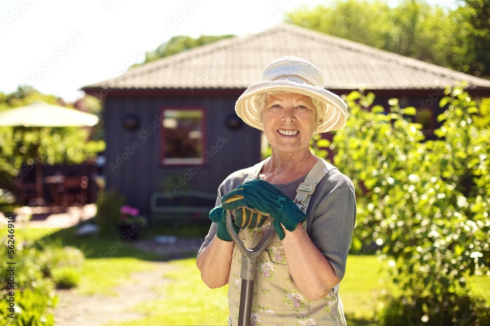 后院里拿着园艺工具的快乐老妇人