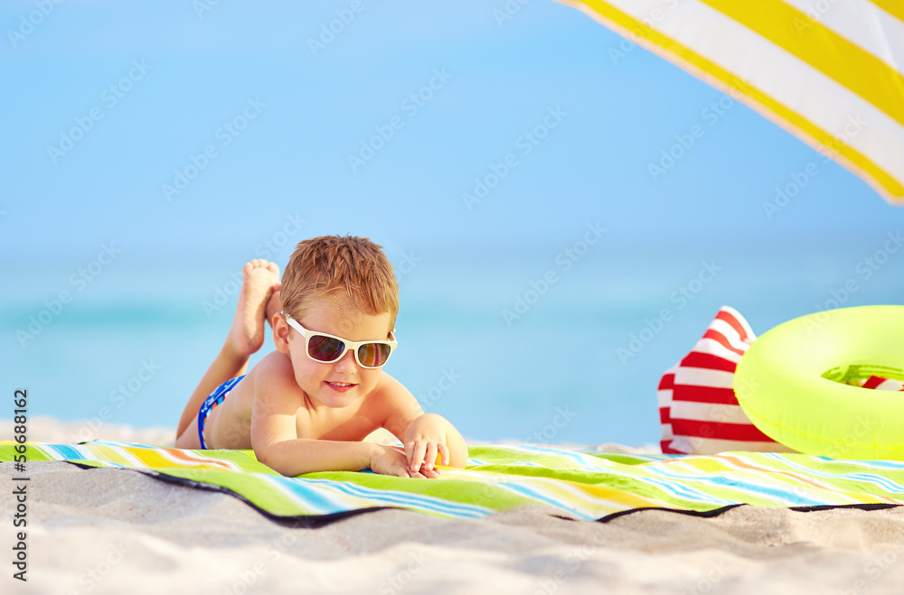 戴着墨镜的可爱孩子在五颜六色的海滩上休息