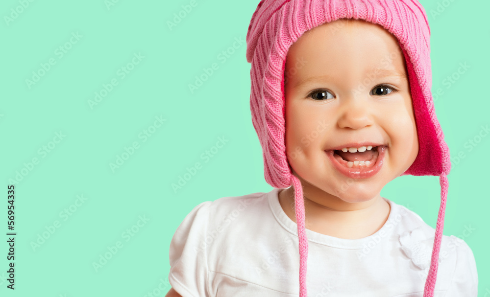戴着粉色冬季针织帽的有趣快乐的女婴大笑