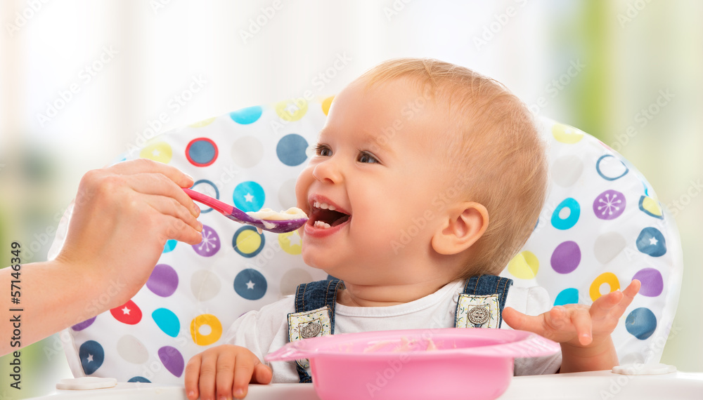 快乐的妈妈用勺子喂有趣的宝宝