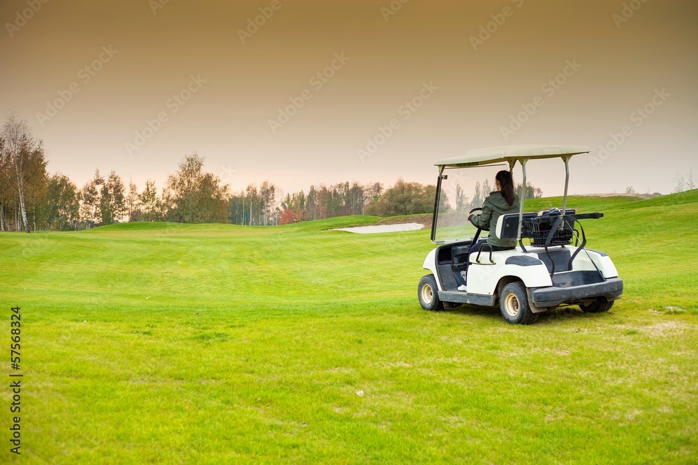 年轻女子在球场上驾驶高尔夫球车