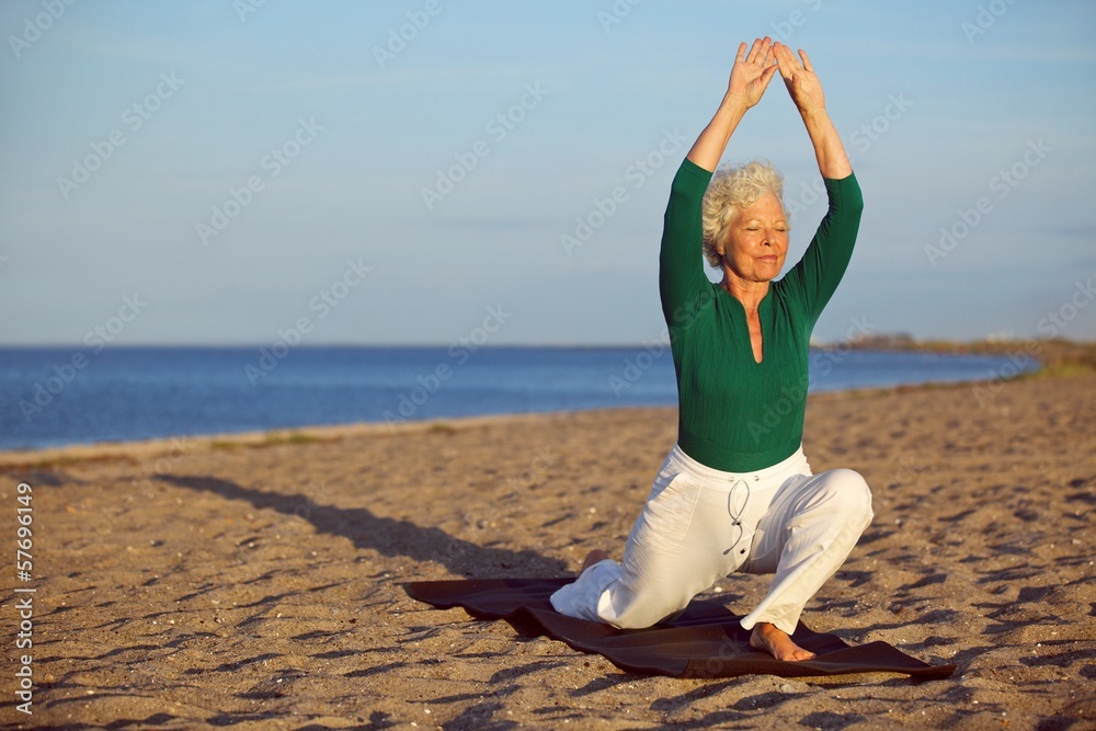 老年妇女在海滩上伸展身体