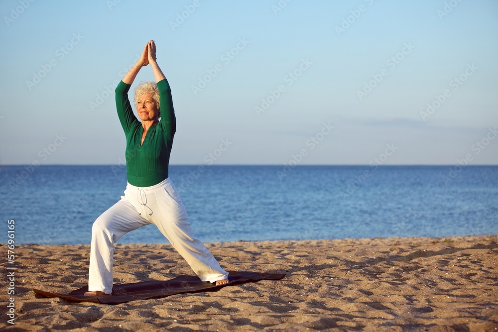 成熟的女人在海滩上伸展身体