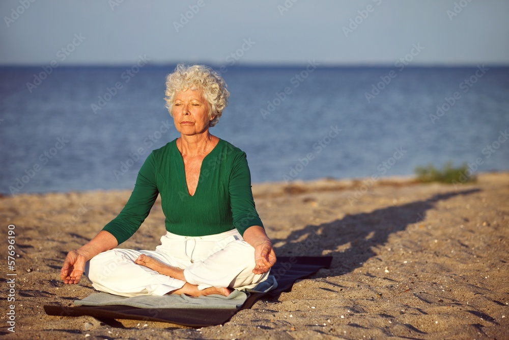 海滩上的老年妇女在海边冥想