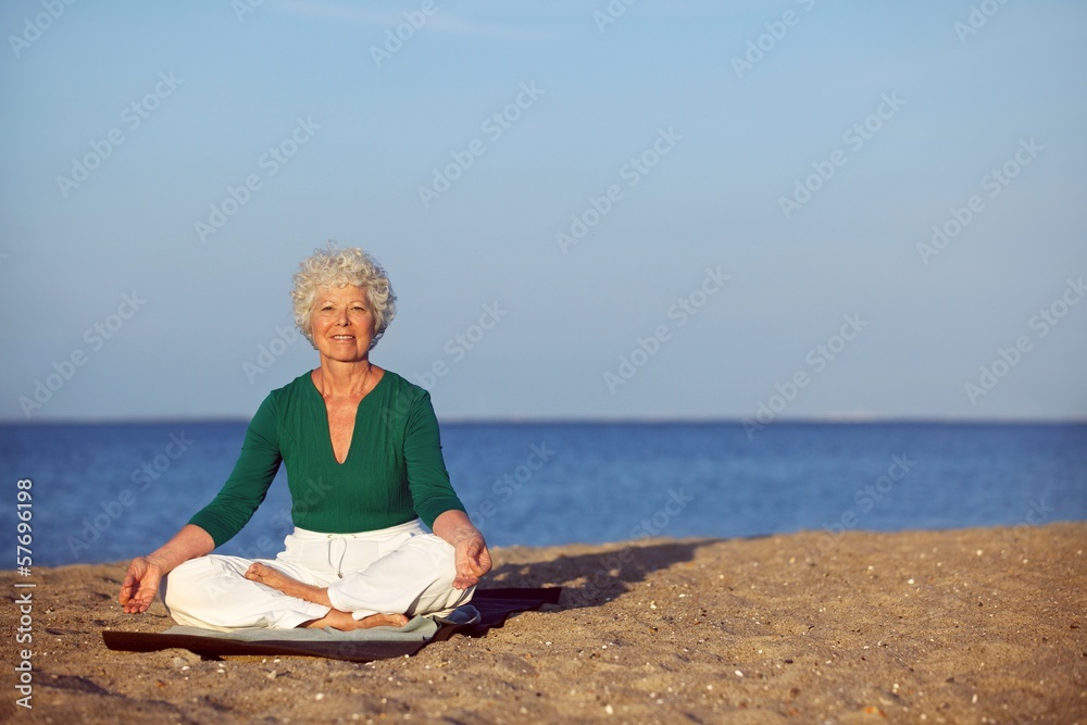Senior woman meditating on beautiful beach