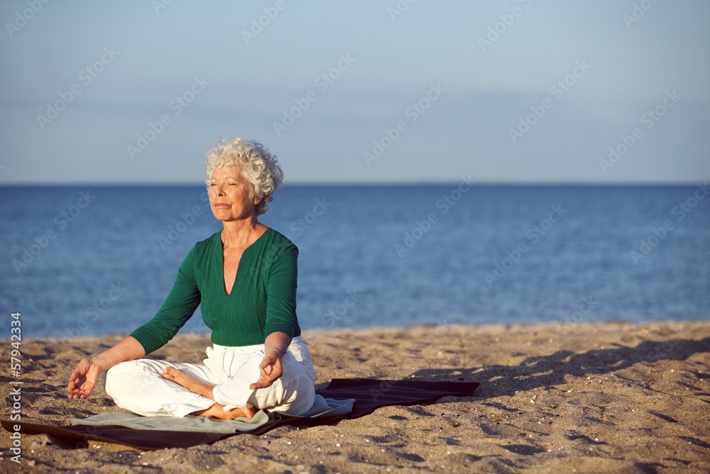 一位在海滩上冥想的白人高级女性