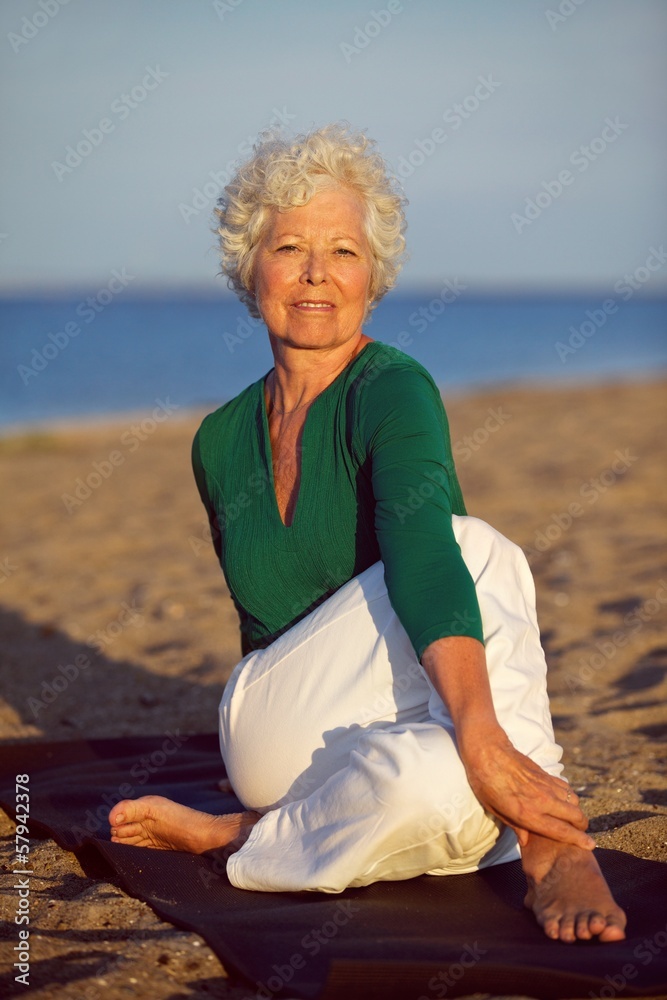 老年妇女在海滩上享受瑜伽