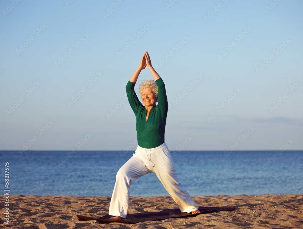 老年妇女在海滩背景下伸展身体