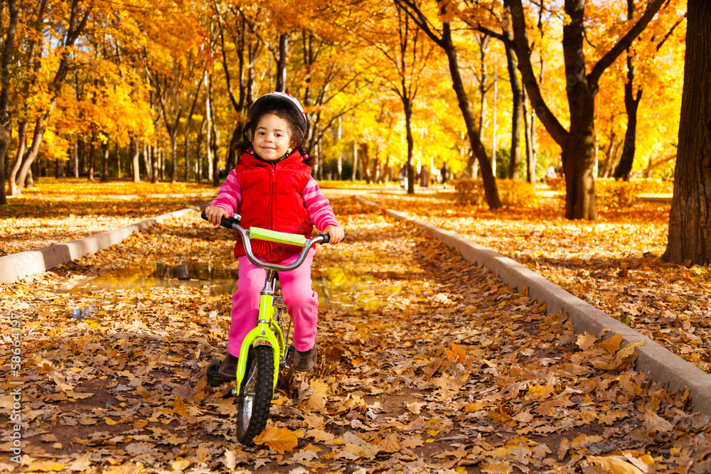 Girl riding bicycle on autumn rode