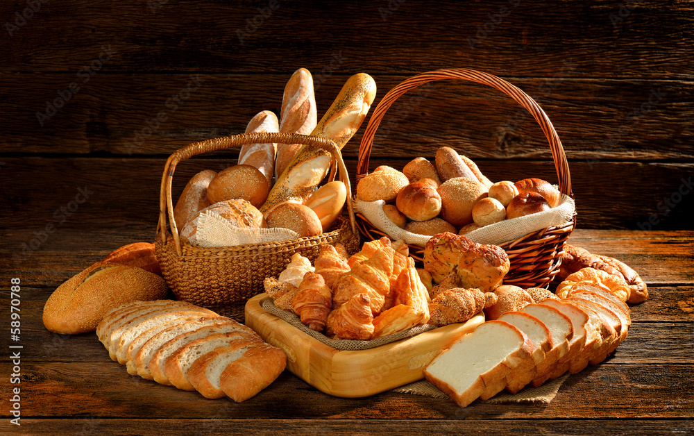 各种各样的面包放在旧木背景的柳条篮子里。