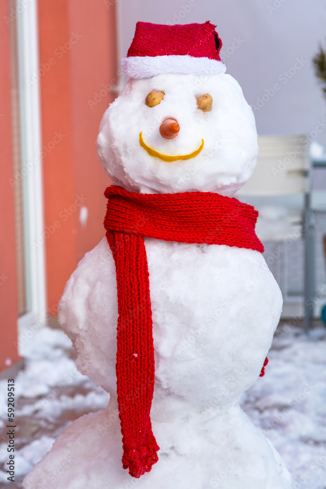Snowman in red hat and scarf on the balcony