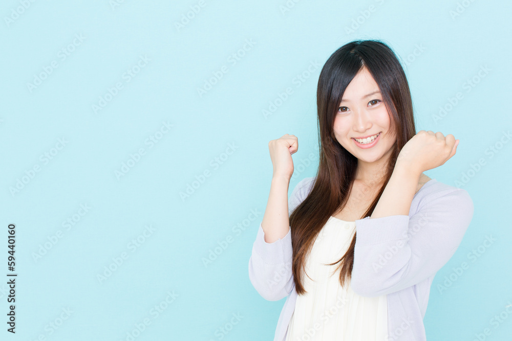 年轻的亚洲女人在蓝色背景下欢呼