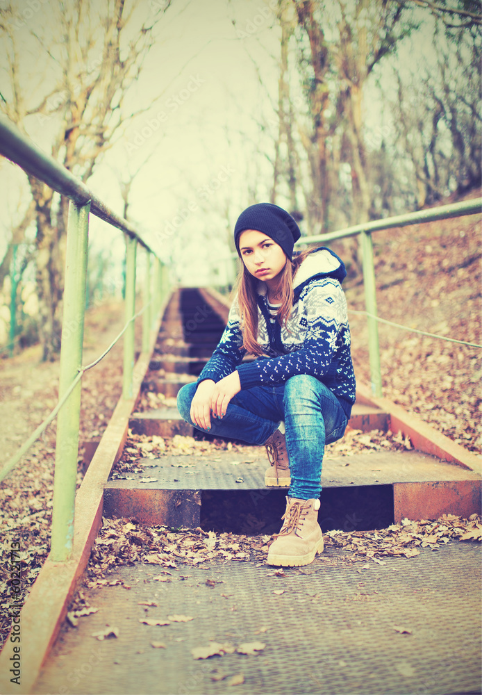 戴帽子的孤独少女坐在楼梯上，悲伤的秋天