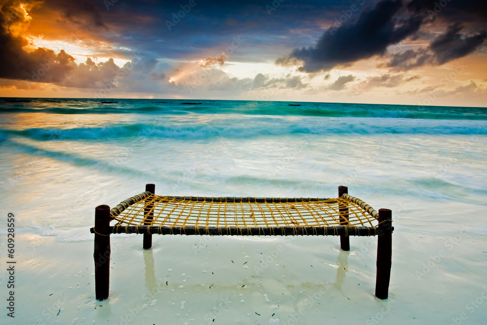 沙滩上的床在戏剧性的天空下触摸大海