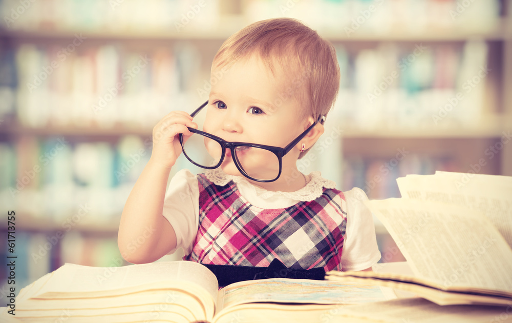 戴眼镜的有趣女婴在图书馆看书
