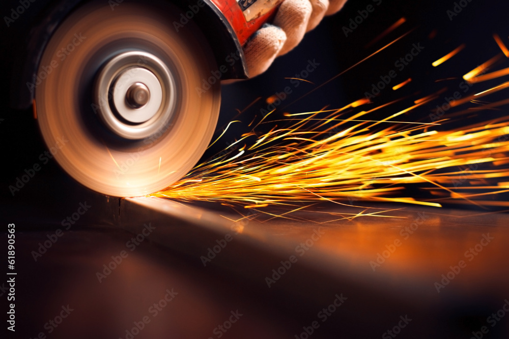 工人用研磨机切割金属。研磨铁时产生火花