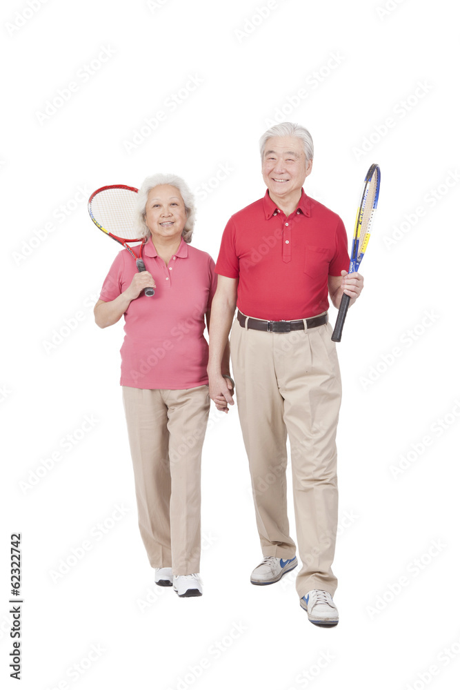 。一对老年夫妇拿着网球拍。