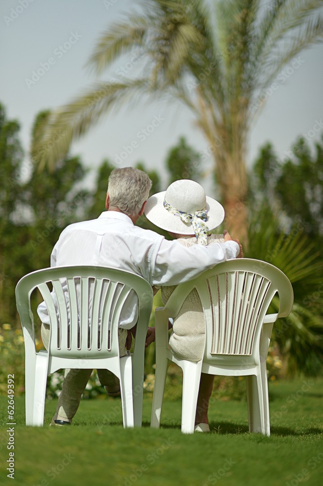 老年夫妇坐在热带酒店花园
