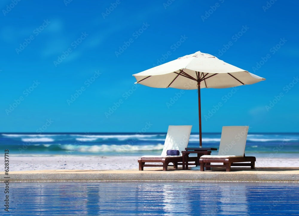 海滩附近带白伞的两把椅子