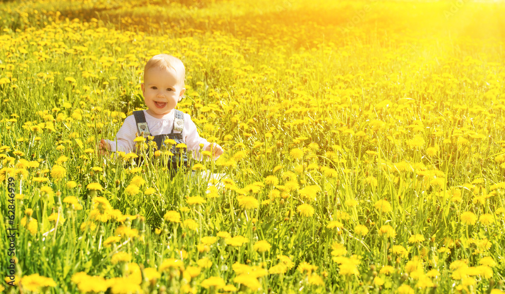 baby girl on a green meadow with yellow flowers dandelions on th