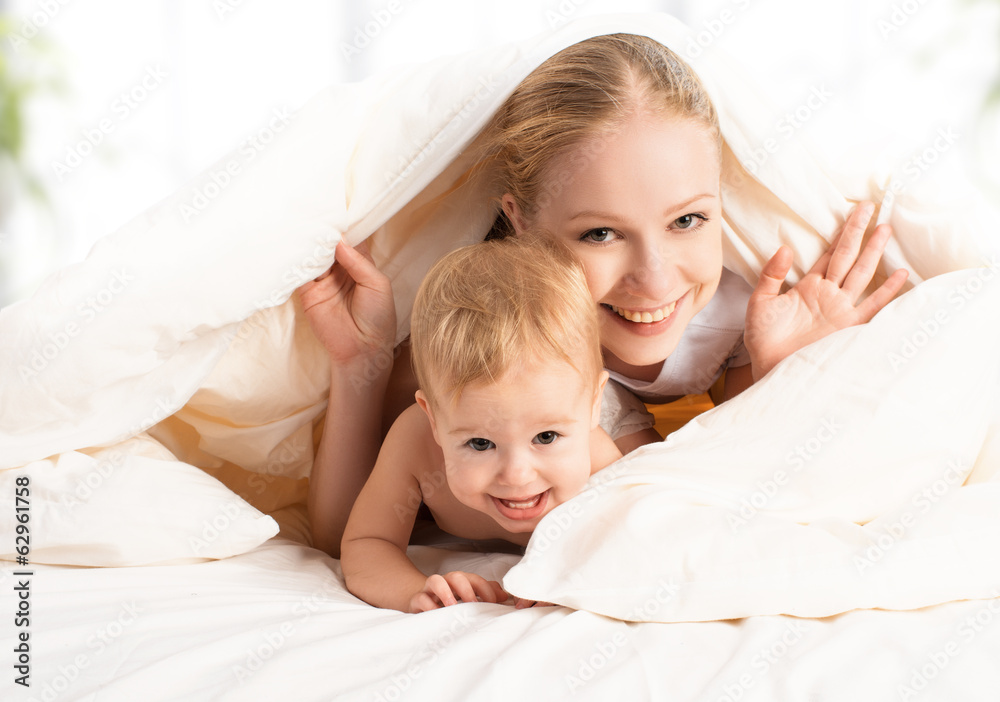 happy family mother and baby under blankets in bed