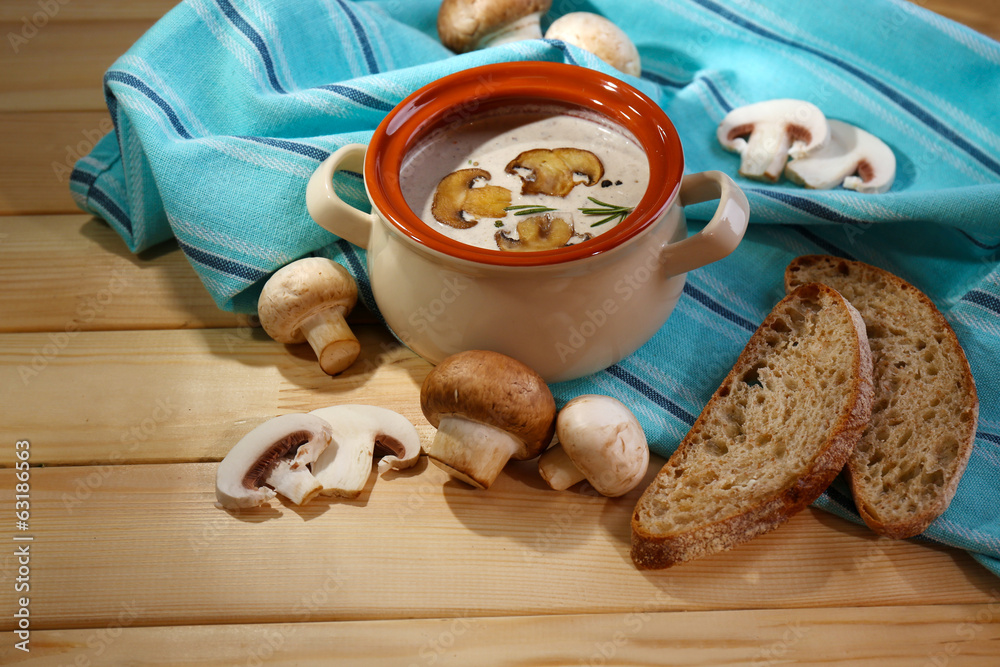 Mushroom soup in pot, on napkin,  on wooden background