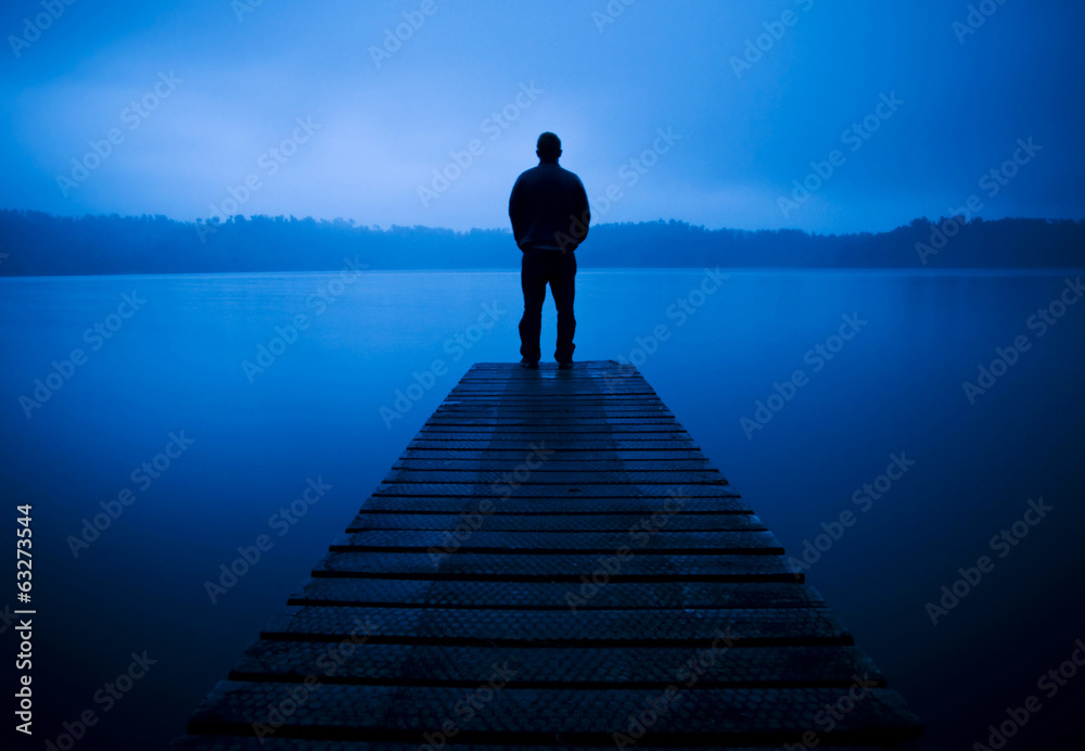 男人站在宁静湖畔的码头上