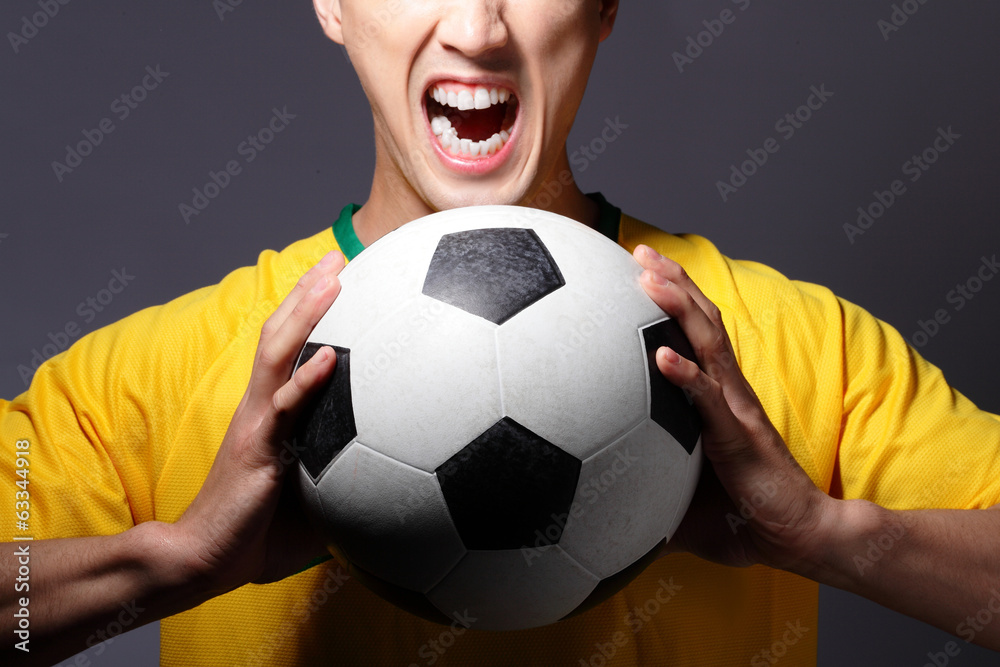 Excited sport man shouting and holding soccer