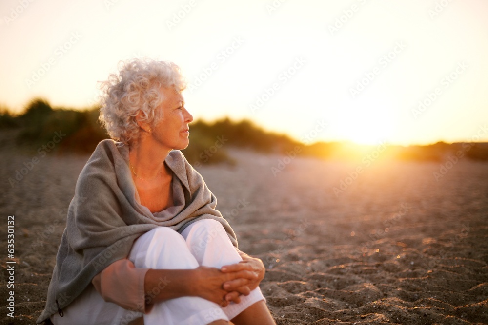 一位老妇人坐在海滩上，看着远处的文案空间