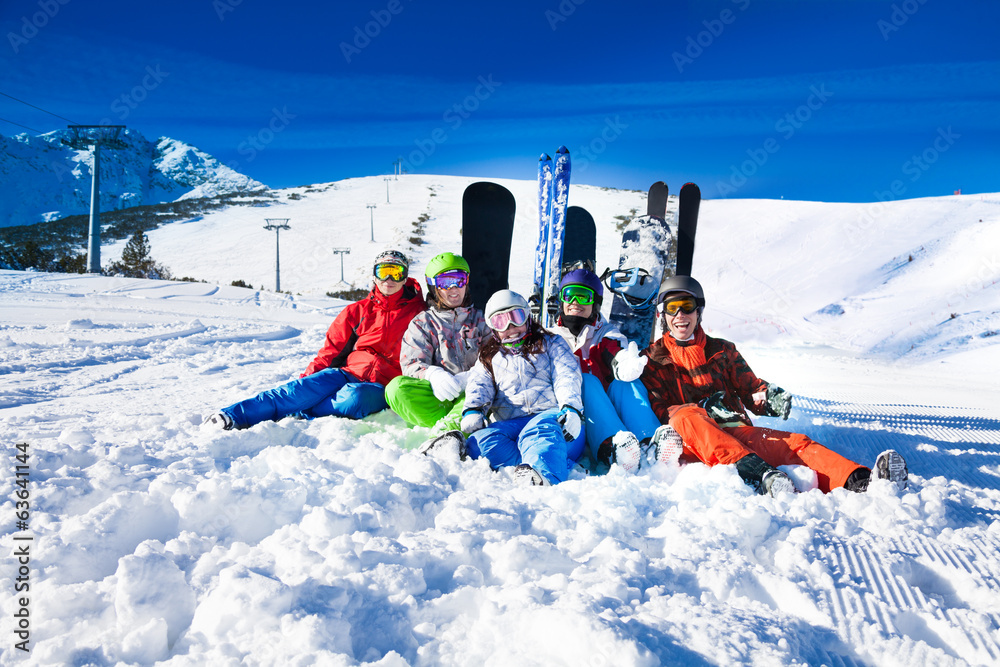 快乐的朋友们坐在滑雪板和滑雪板上
