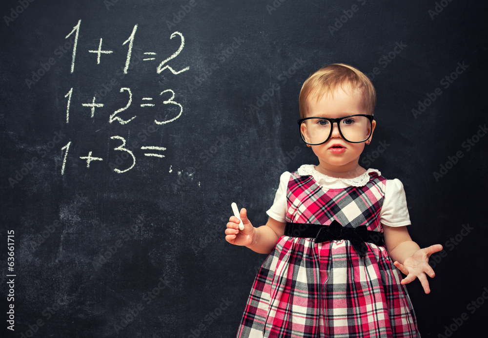 戴着眼镜和粉笔的女婴在学校黑板上用算术