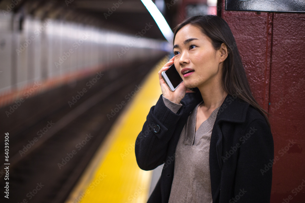 亚洲年轻女子在地铁站台上讲手机