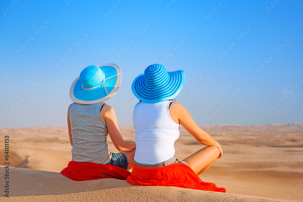 两个戴帽子的女孩在沙漠狩猎中放松