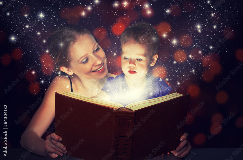 母亲和孩子宝贝女儿在黑暗中阅读魔法书
