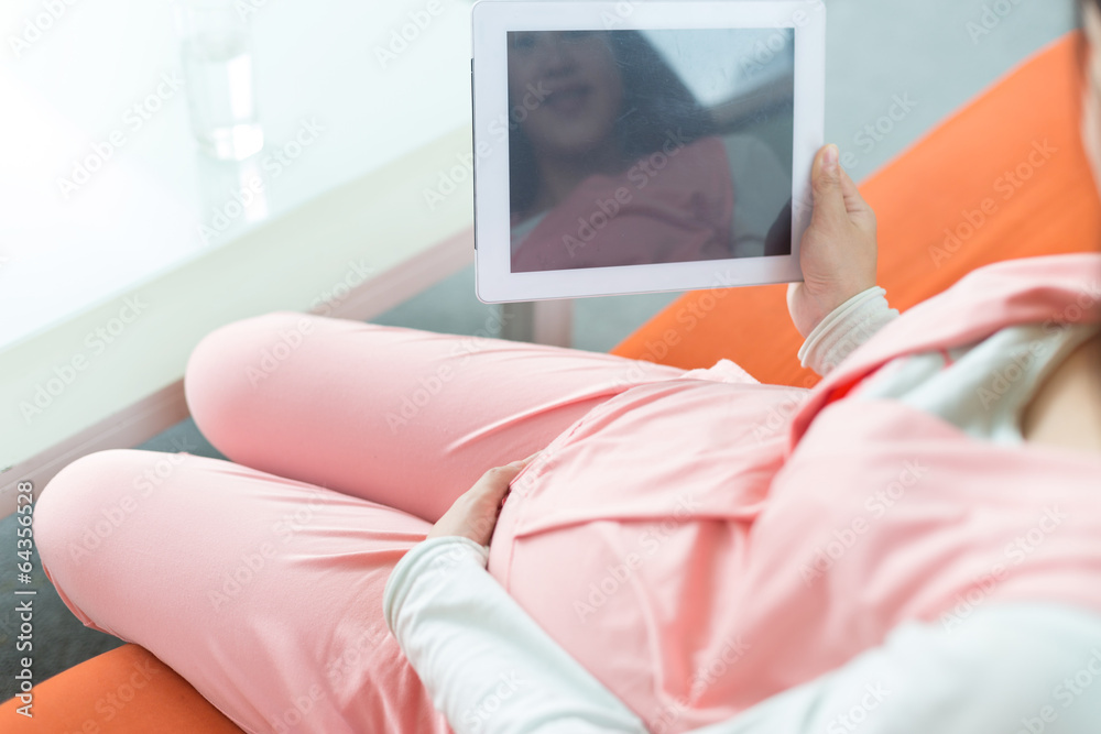 快乐的孕妇看着相机，用数字平板电脑