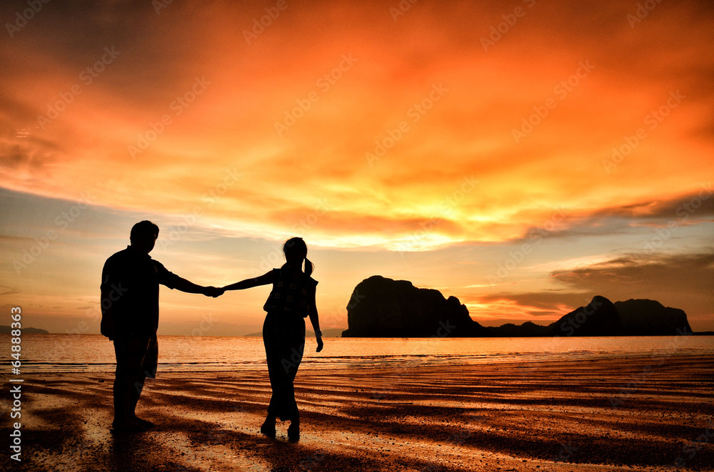 海滩上日落时牵手的浪漫情侣