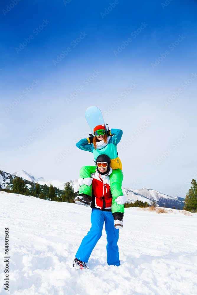 Snowboarder holding girl on his shoulders