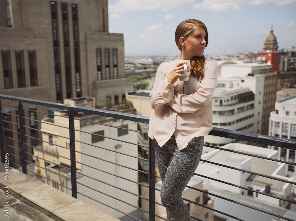 女人在阳台上喝咖啡欣赏城市美景