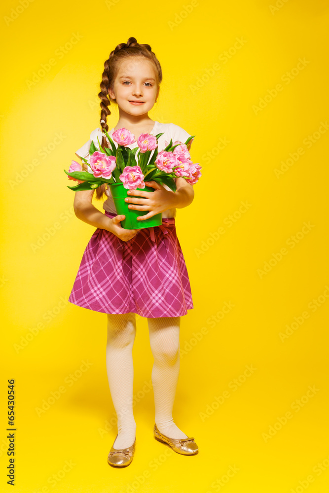 带辫子的可爱女孩提桶和粉色郁金香