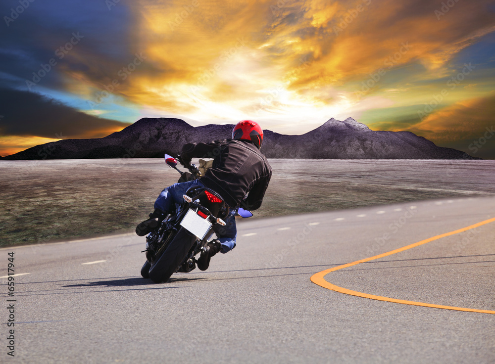 年轻人骑摩托车在柏油路弯道w后视图