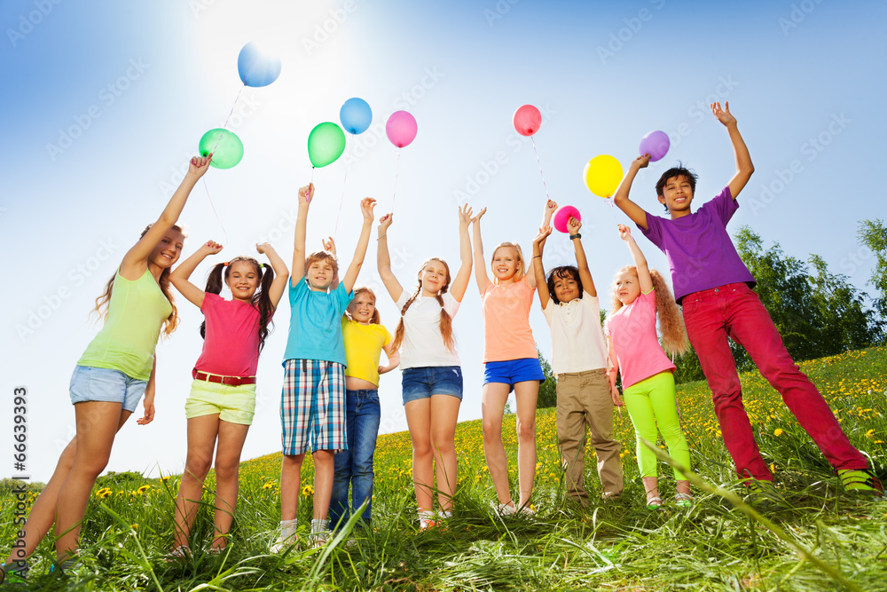 孩子们高举双臂站在气球前