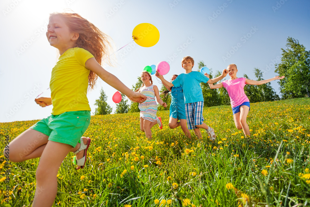 兴奋的孩子们带着气球在田野里奔跑