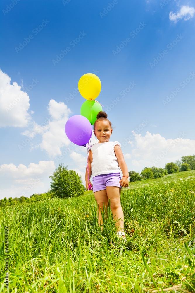 抱着三个会飞的气球的可爱小女孩