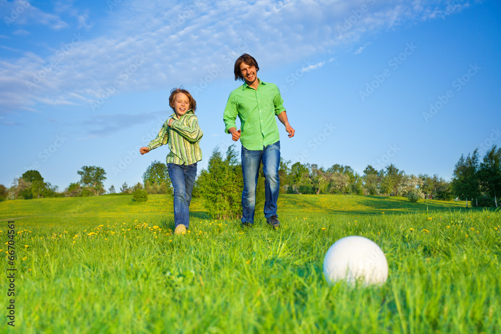 父亲和孩子在公园里踢足球