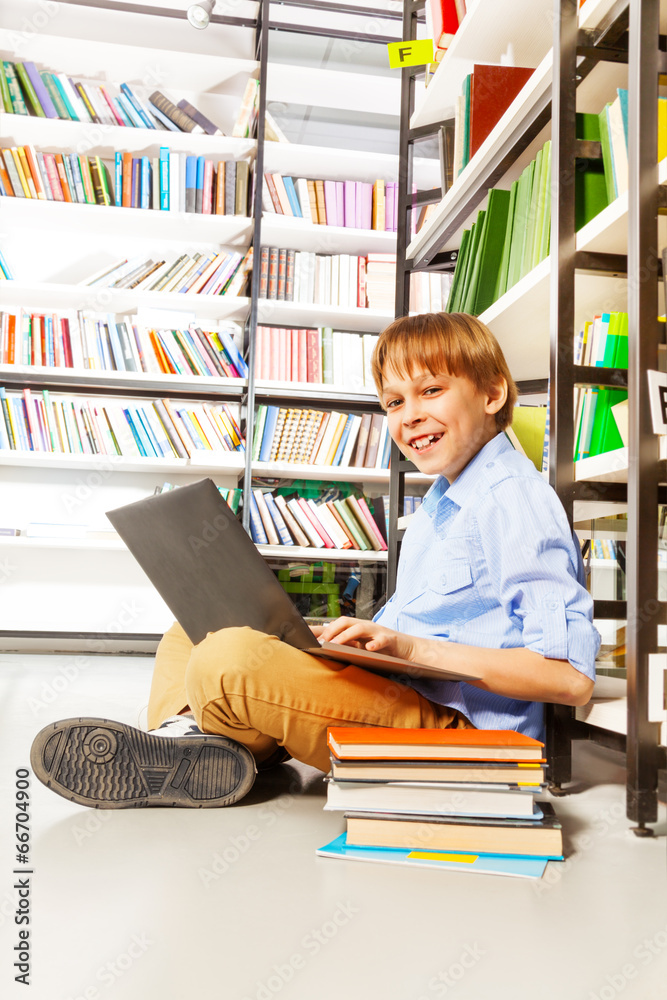 微笑的男孩坐在地板上，笔记本电脑