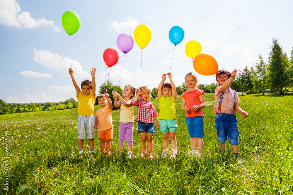 七个孩子带着气球在绿地里